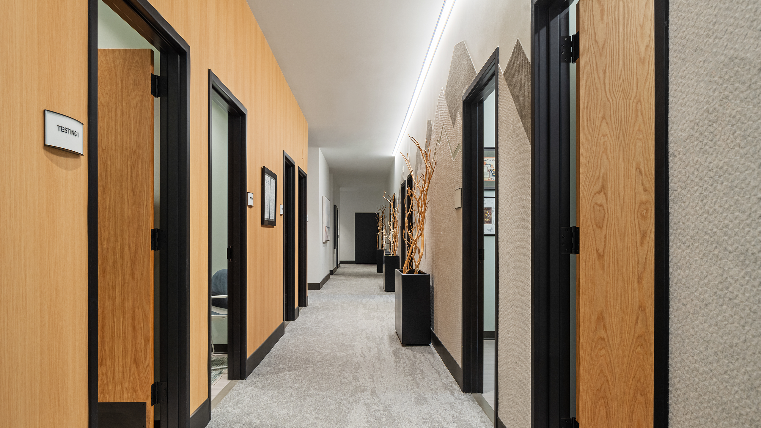 Second-floor hallway at Summit Hyperbarics & Wellness, featuring testing rooms on the left and offices on the right, with modern wood paneling and soft lighting.
