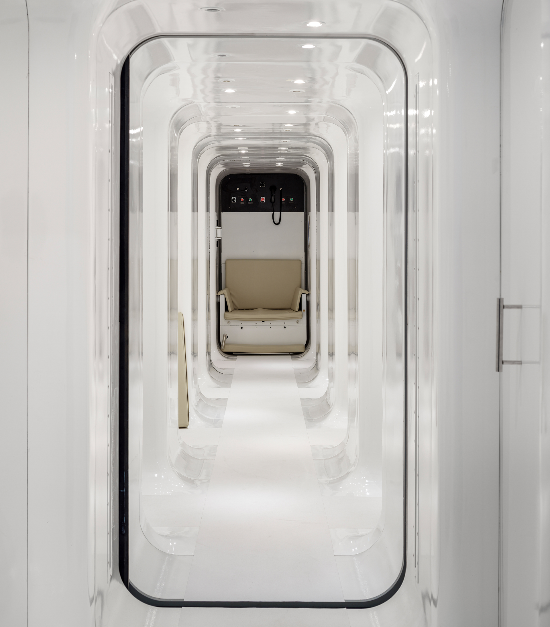 Interior of our multiperson hyperbaric oxygen chamber featuring a beige reclining chair and control panel.
