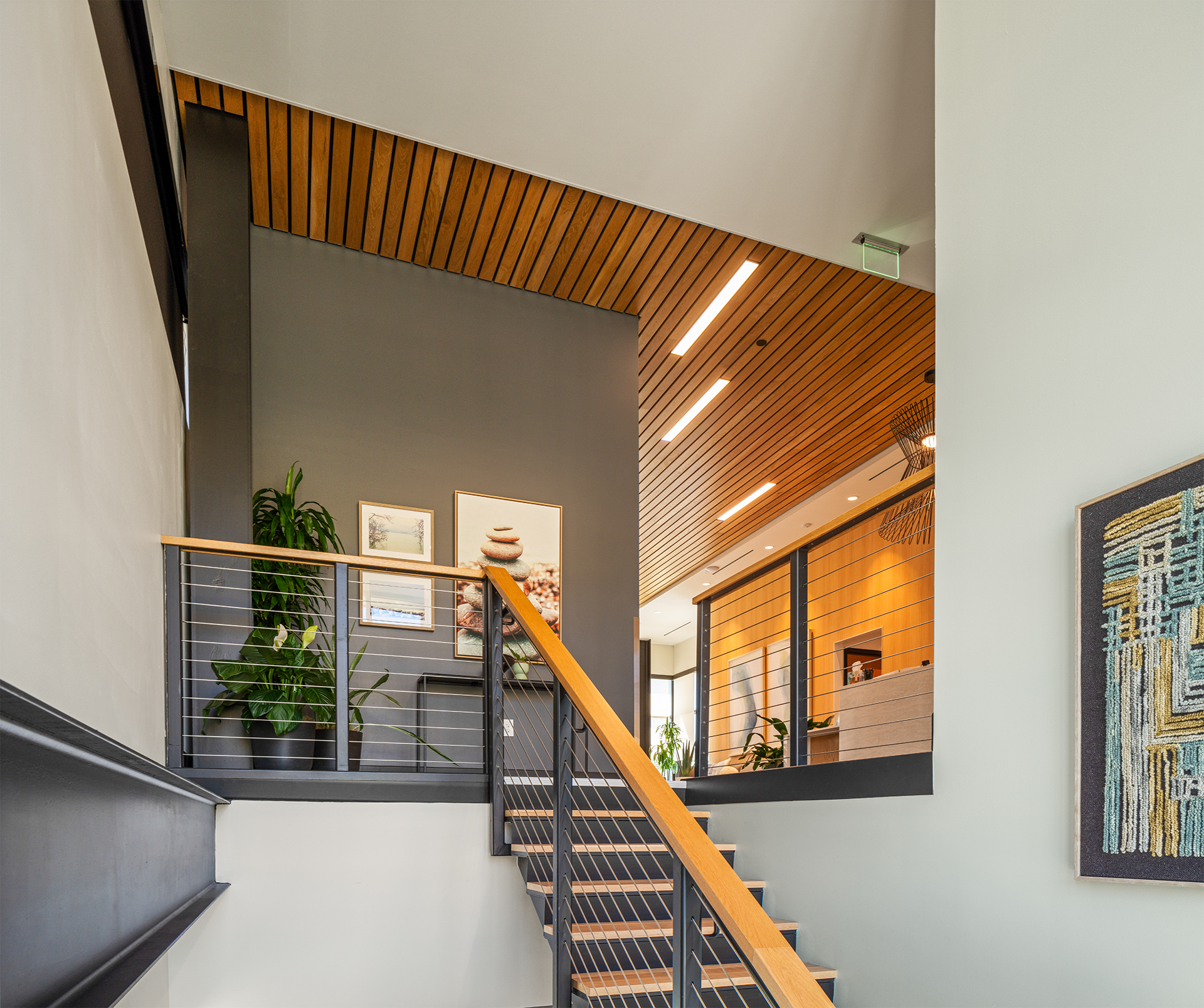 Modern interior staircase with wooden railings and artwork on the wall in a wellness facility.