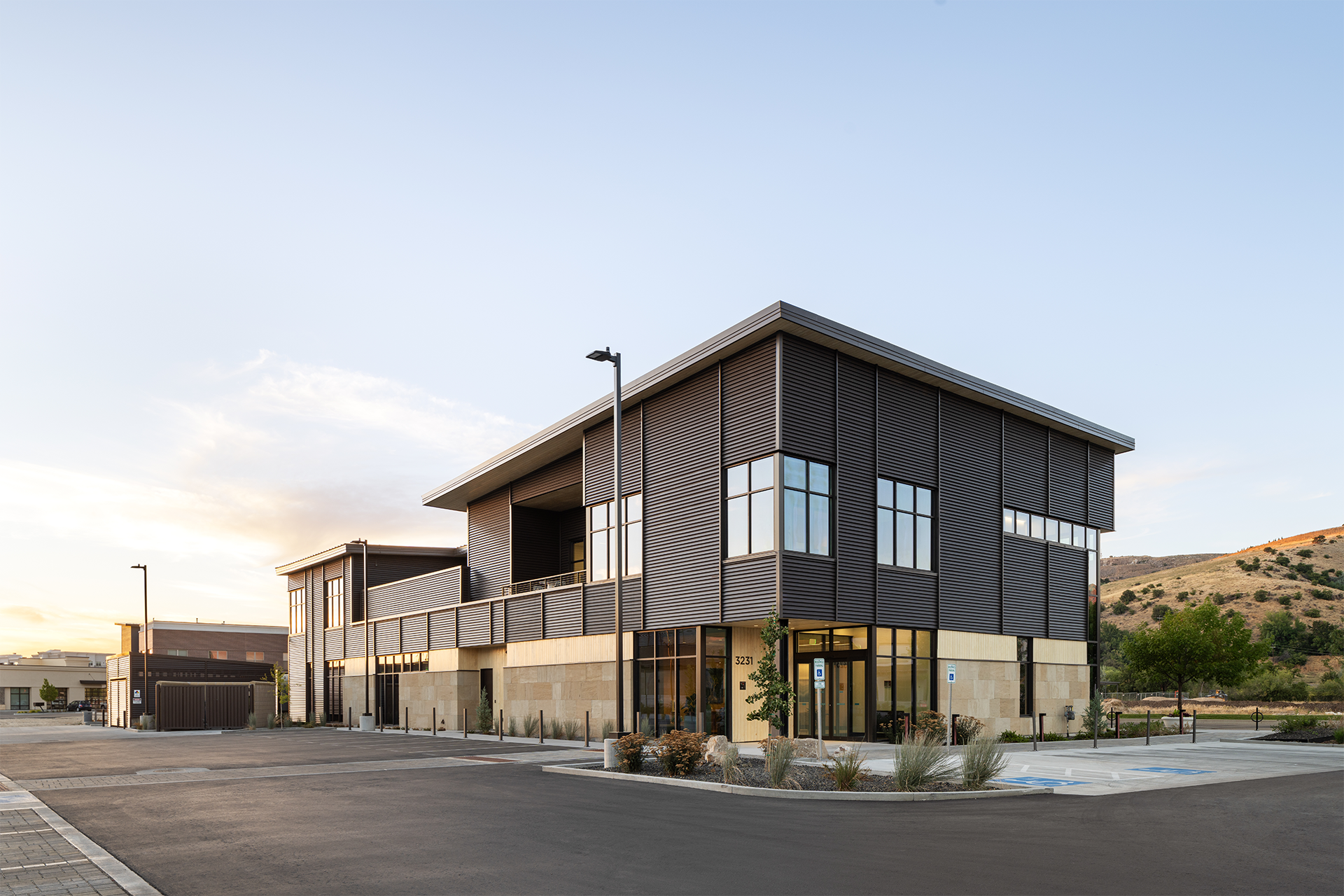 Exterior view of the Summit Hyperbarics & Wellness building, facing northwest, with modern architecture, large windows, and a scenic hillside backdrop.
